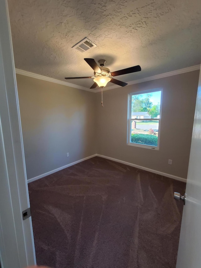 empty room featuring dark carpet, ornamental molding, and a textured ceiling