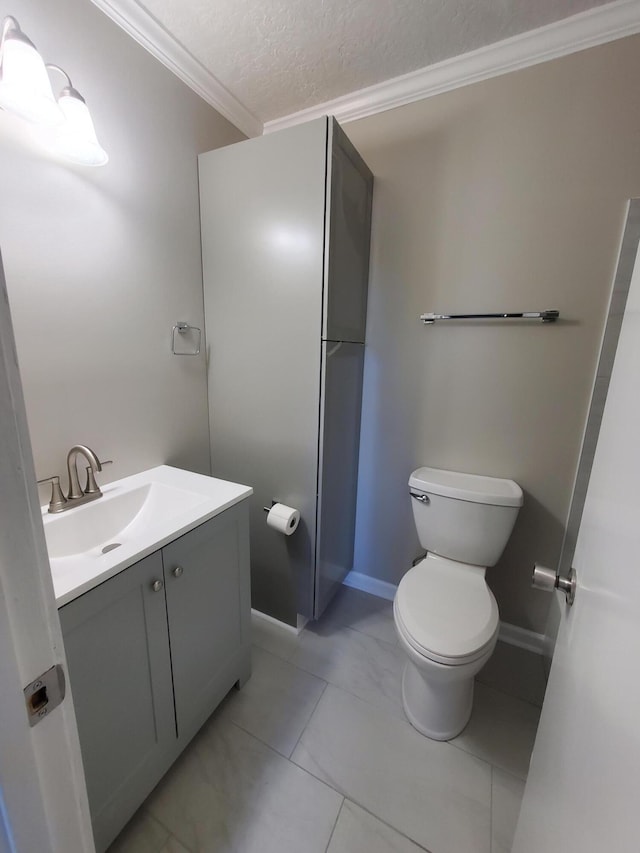 bathroom with a textured ceiling, vanity, toilet, and crown molding