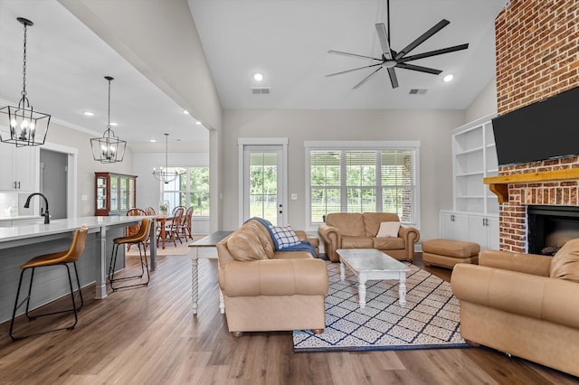 7181 Moontown Rd, Appling, GA 30802 - living room with vaulted ceiling, a chandelier, ceiling fan, wood finished floors, and a brick fireplace