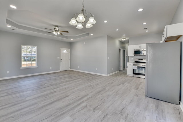 kitchen featuring stainless steel appliances, white cabinets, open floor plan, light countertops, and a raised ceiling