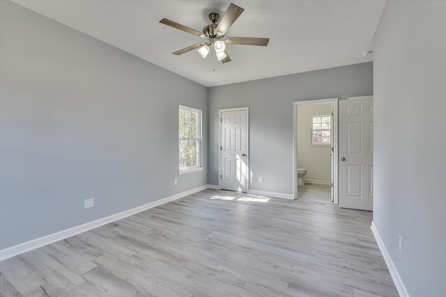 unfurnished bedroom with multiple windows, light wood-style flooring, and baseboards