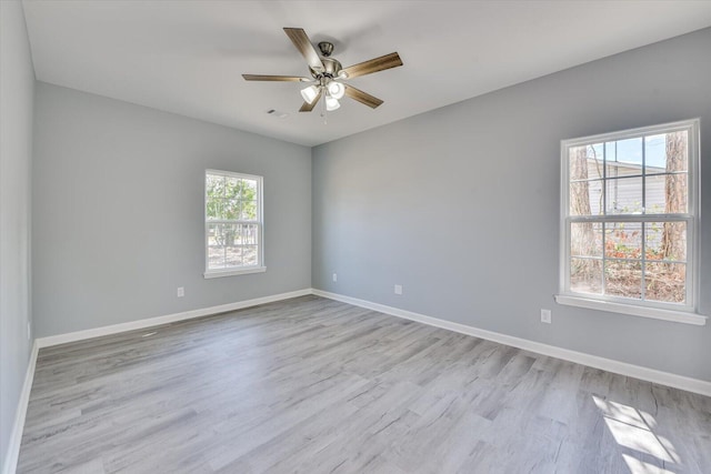 empty room featuring light wood-type flooring, a ceiling fan, and baseboards