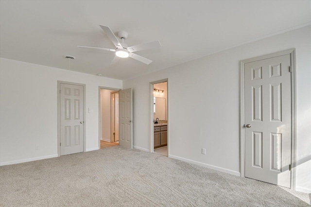 unfurnished bedroom with connected bathroom, baseboards, light carpet, a ceiling fan, and a sink