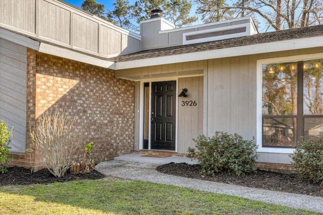 entrance to property featuring brick siding and a chimney