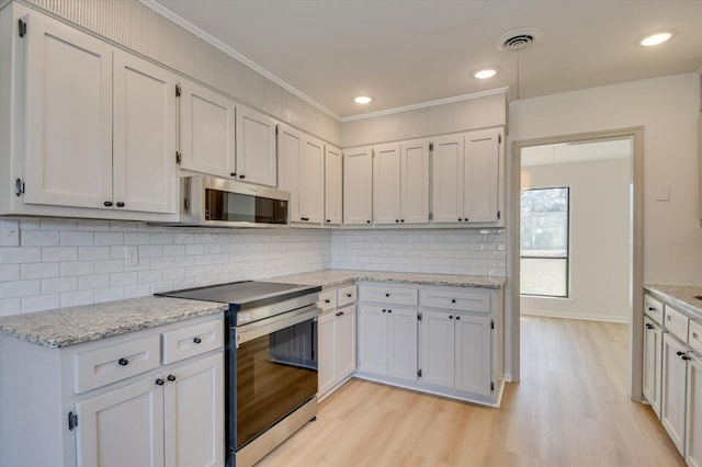 kitchen featuring light wood-type flooring, visible vents, ornamental molding, backsplash, and appliances with stainless steel finishes