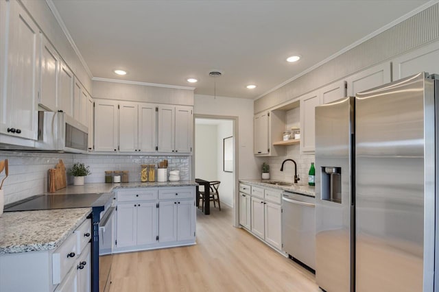 kitchen featuring visible vents, light wood-type flooring, a sink, appliances with stainless steel finishes, and crown molding