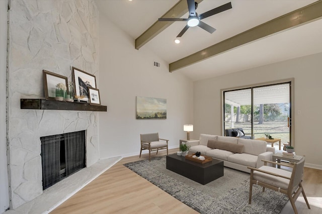 living area featuring a high end fireplace, beam ceiling, visible vents, and light wood finished floors