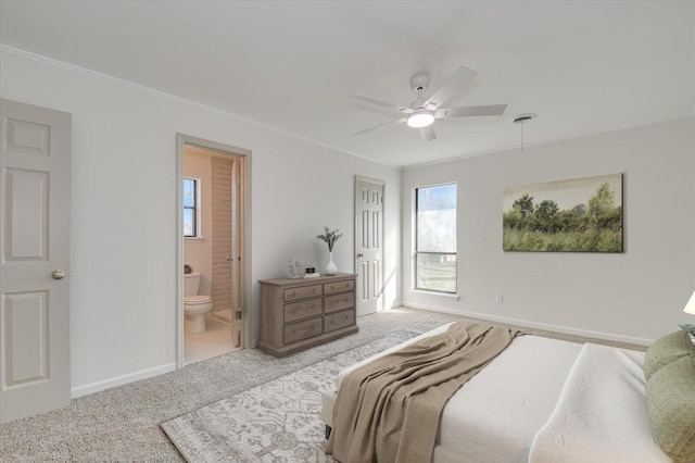 bedroom featuring ornamental molding, ensuite bath, carpet floors, baseboards, and ceiling fan