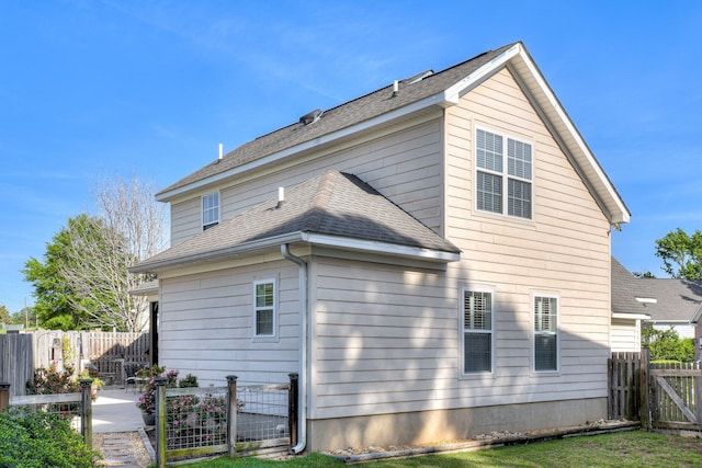 rear view of property with a fenced backyard, a gate, a patio, and roof with shingles