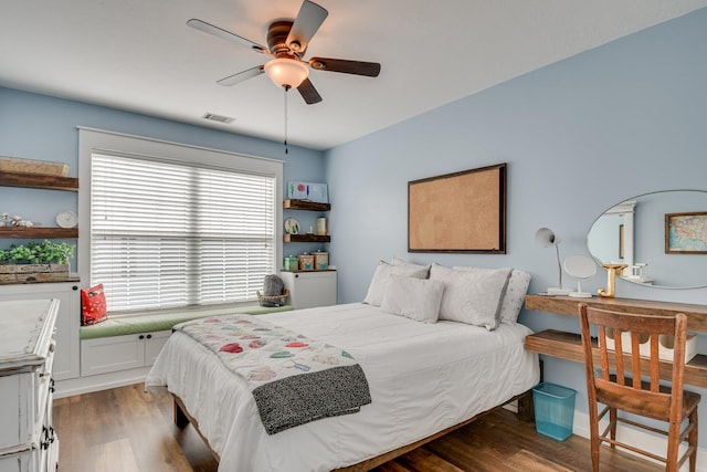 bedroom with ceiling fan, visible vents, and wood finished floors