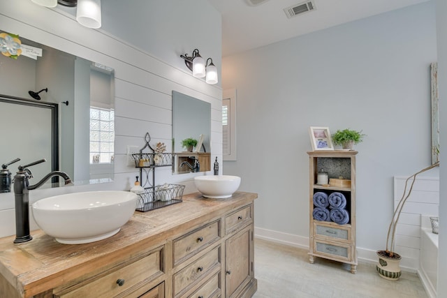 full bathroom featuring a sink, baseboards, a shower with shower door, and visible vents