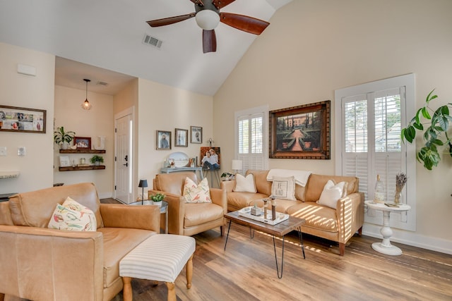 living area featuring ceiling fan, visible vents, wood finished floors, high vaulted ceiling, and baseboards