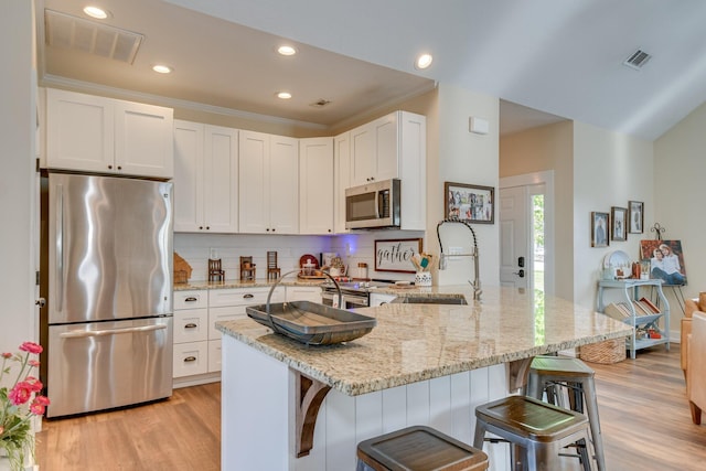 kitchen with stainless steel appliances, visible vents, a sink, and light wood-type flooring