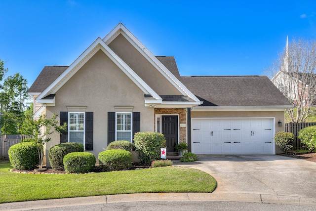 traditional-style home featuring fence, stone siding, a garage, stucco siding, and concrete driveway