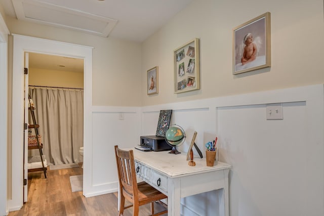 office space featuring attic access, wood finished floors, and a wainscoted wall
