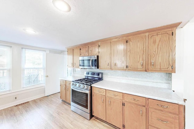 kitchen featuring decorative backsplash, stainless steel appliances, and light hardwood / wood-style floors