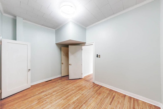 empty room with crown molding and light hardwood / wood-style flooring