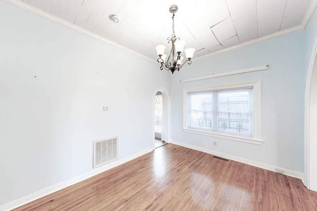 empty room with crown molding, hardwood / wood-style floors, and a notable chandelier