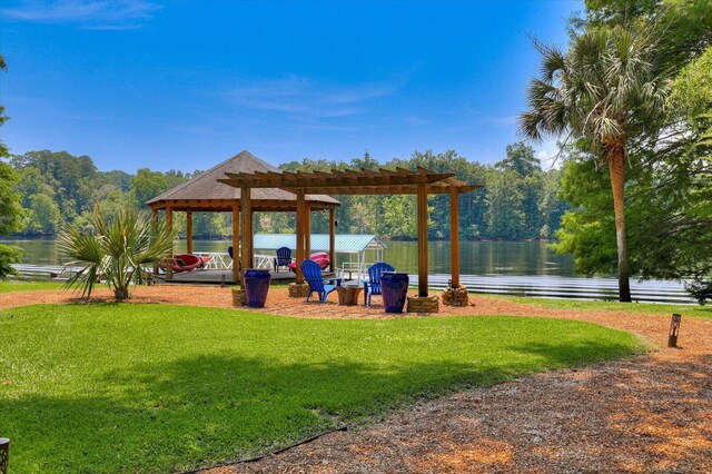 view of community featuring a pergola, a water view, and a lawn