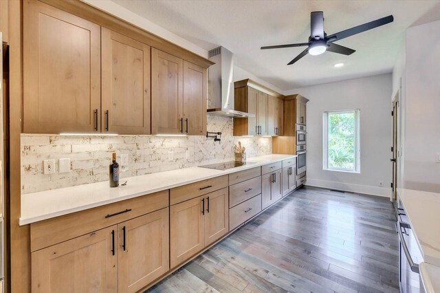 kitchen with ceiling fan, wall chimney range hood, black electric cooktop, decorative backsplash, and hardwood / wood-style flooring