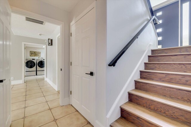 stairs with tile patterned floors and washer and dryer