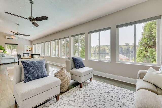 living room featuring light hardwood / wood-style flooring, vaulted ceiling, ceiling fan, a textured ceiling, and a wall mounted AC