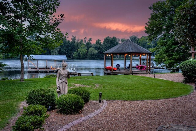 view of dock with a lawn and a water view