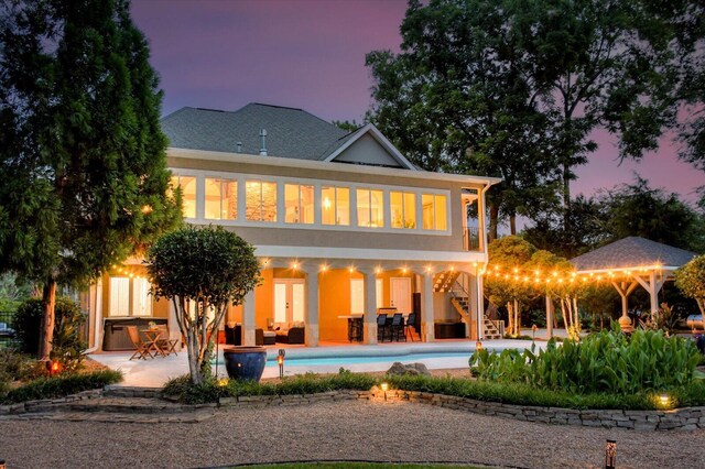 back house at dusk featuring an outdoor living space and a patio