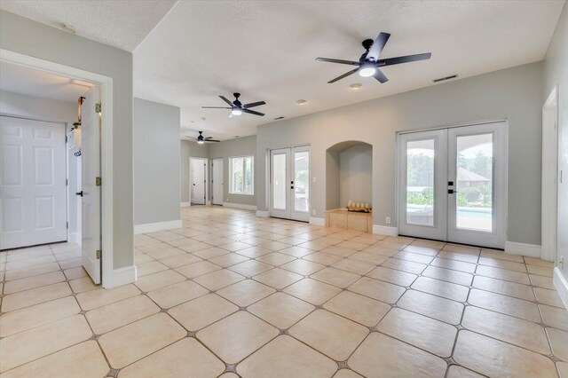 interior space featuring ceiling fan, french doors, light tile patterned floors, and a textured ceiling