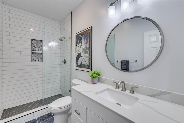 bathroom featuring tiled shower, tile patterned flooring, vanity, and toilet