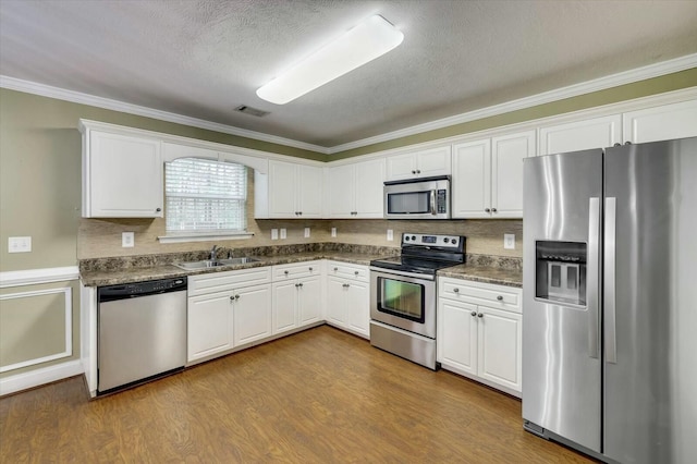 kitchen featuring a textured ceiling, crown molding, white cabinetry, and stainless steel appliances