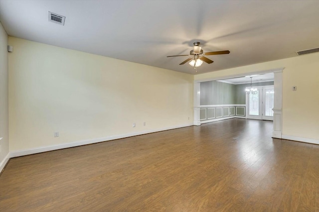 spare room with dark wood-type flooring and ceiling fan with notable chandelier