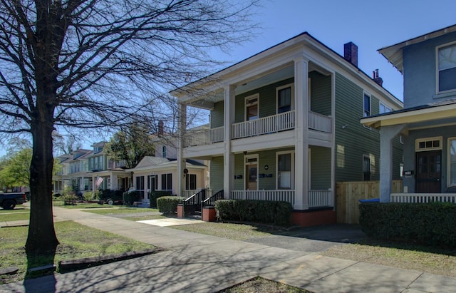 view of front of house featuring a balcony, a chimney, and covered porch