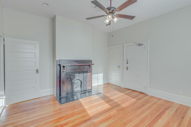 unfurnished living room with wood finished floors, ceiling fan, baseboards, and a fireplace