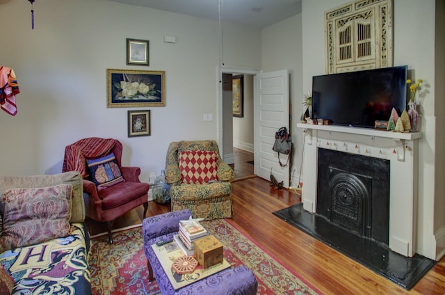living area featuring a fireplace with raised hearth and wood finished floors