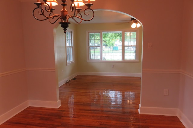 unfurnished room featuring ceiling fan with notable chandelier and dark hardwood / wood-style floors