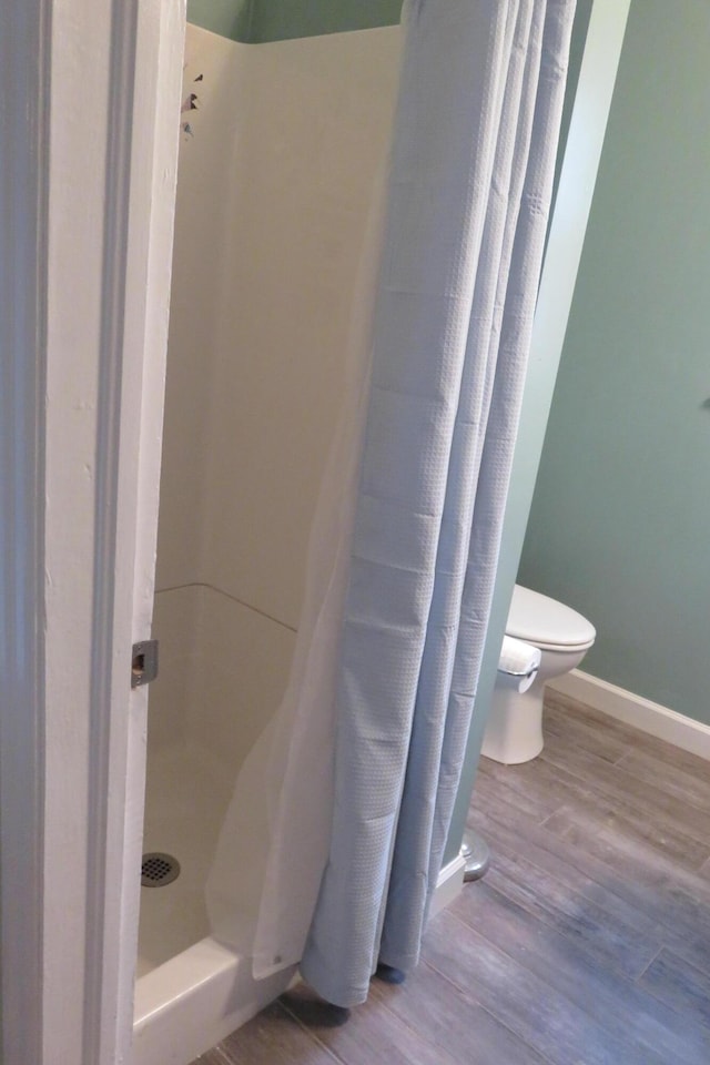 bathroom featuring a shower with shower curtain, toilet, and hardwood / wood-style floors