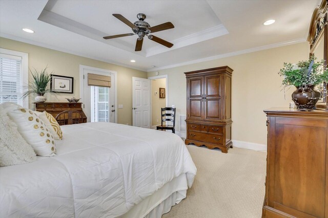 carpeted bedroom with multiple windows, a tray ceiling, ceiling fan, and crown molding