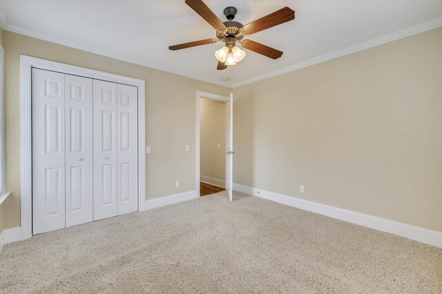 unfurnished bedroom with carpet flooring, ceiling fan, a closet, and ornamental molding