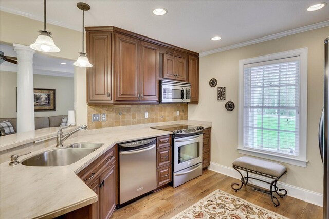 kitchen with ornate columns, sink, stainless steel appliances, backsplash, and light wood-type flooring