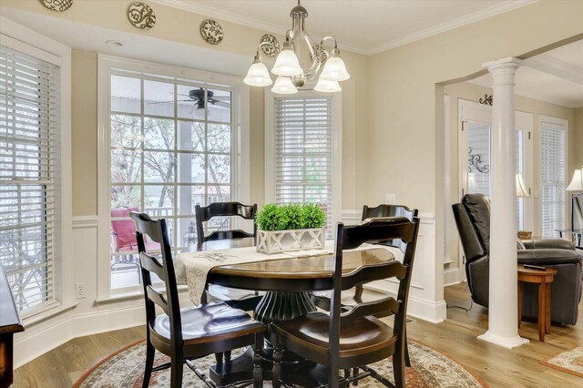 dining room with decorative columns, ornamental molding, ceiling fan with notable chandelier, and light wood-type flooring