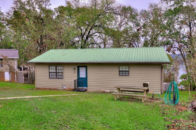 rear view of property featuring cooling unit and a yard