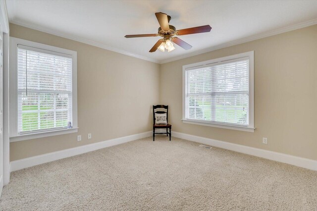 carpeted spare room with plenty of natural light, ornamental molding, and ceiling fan