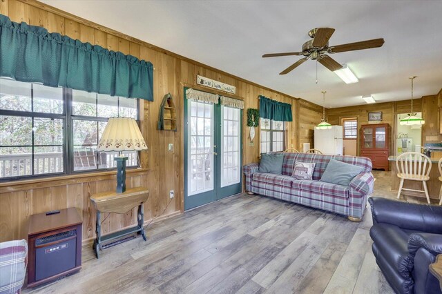 living room featuring wood-type flooring, french doors, ceiling fan, and wood walls