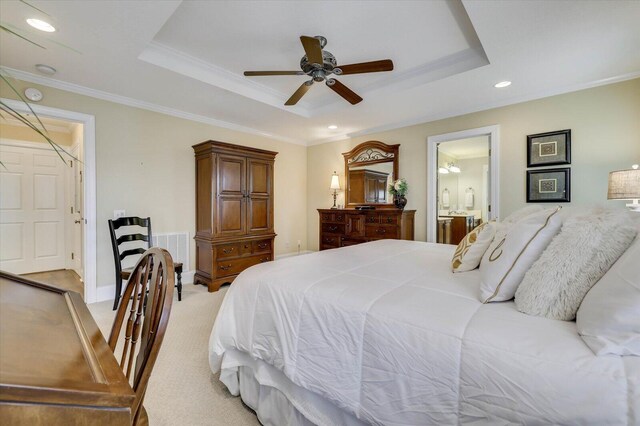 carpeted bedroom featuring ceiling fan, ornamental molding, ensuite bathroom, and a tray ceiling