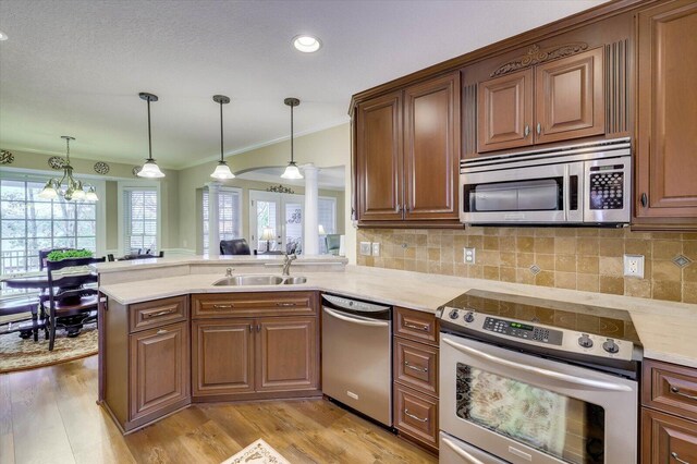 kitchen featuring kitchen peninsula, stainless steel appliances, and decorative light fixtures