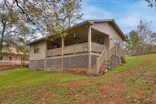 back of property with ceiling fan and a yard