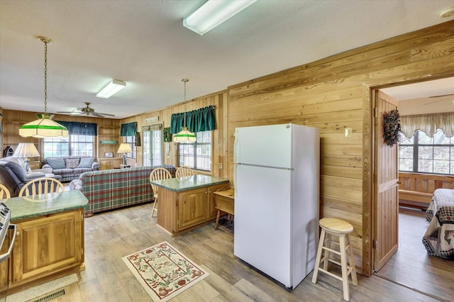 kitchen featuring wooden walls, white fridge, light hardwood / wood-style floors, and a kitchen island