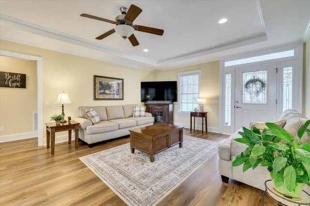 living room featuring ceiling fan, crown molding, and a tray ceiling