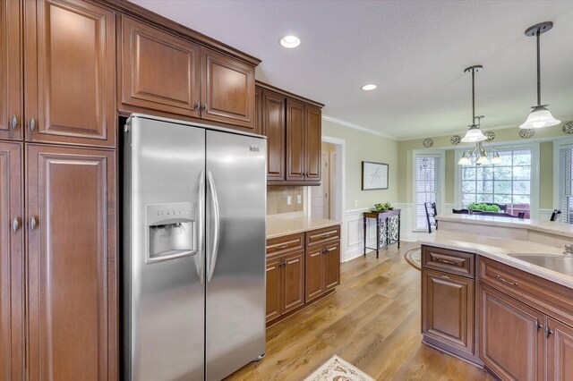 kitchen with light wood-type flooring, backsplash, pendant lighting, a chandelier, and stainless steel fridge with ice dispenser